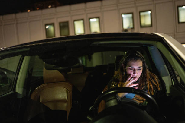 kaukaska nastolatka, siedząca w samochodzie, korzystająca z telefonu komórkowego i paląca papierosa - teenager dark pensive emotional stress zdjęcia i obrazy z banku zdjęć