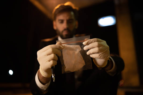 Caucasian male inspector/forensic observing the plastic bag with evidence at the crime scene at the railroad train station