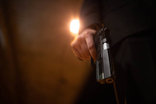 Unrecognizable man in suit holding the gun, in the dark