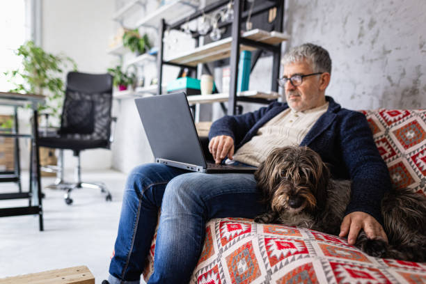 istock Man using laptop while his pet dog enjoys next to him 1367994263