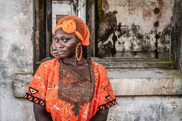 Africa Woman in orange suit and headdress Africa Woman in orange suit and headdress stands by an old building in Takoradi Ghana West Africa african tribe stock pictures, royalty-free photos & images