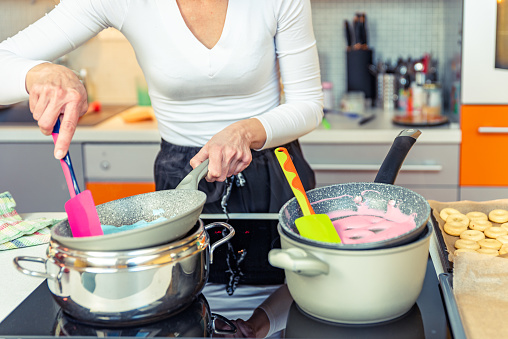 Woman in Domestic Kitchen Melting Colorful Chocolate for Donuts Decoration