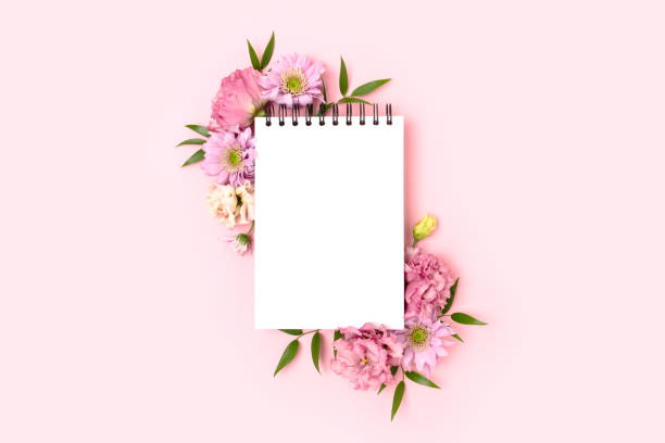Border frame made of eustoma flower and empty notepad mockup on a pink background.