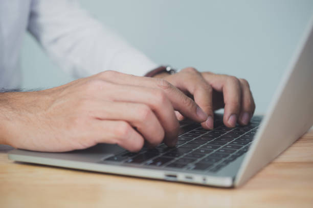 istock Man hands writing on laptop, close up 1367995601