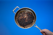 istock Dirty oily burnt metal frying pan held in hand by male hand. 1367996520