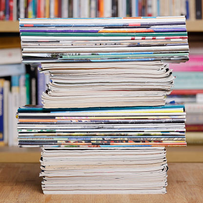 Stack of magazines in front of bookshelf