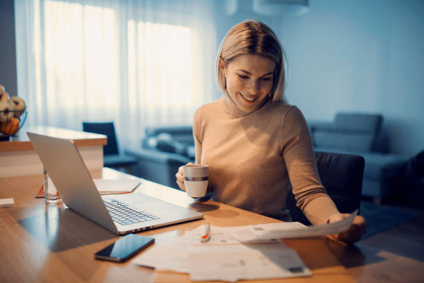 A happy woman doing household budget at her cozy home. stock photo