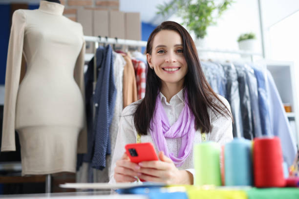 istock Smiling blooming woman holding smartphone at workplace 1367999159