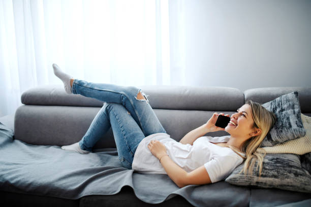 istock A happy woman enjoying the phone conversation while lying down on sofa. 1367999169