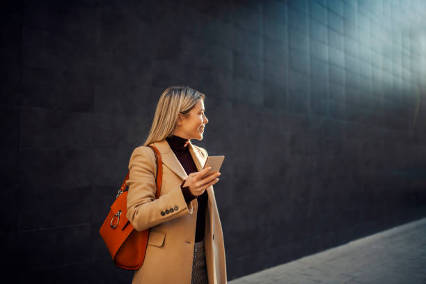 istock A happy woman using her phone outside on cold weather. 1367999353