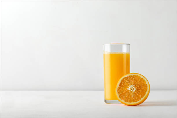 Orange juice for menu with ripe half of orange on white table. Copy space for text.