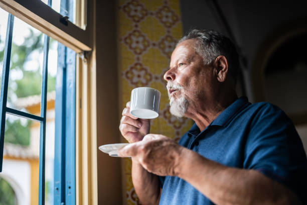 istock Contemplative senior man drinking coffee and looking through the window 1368002909