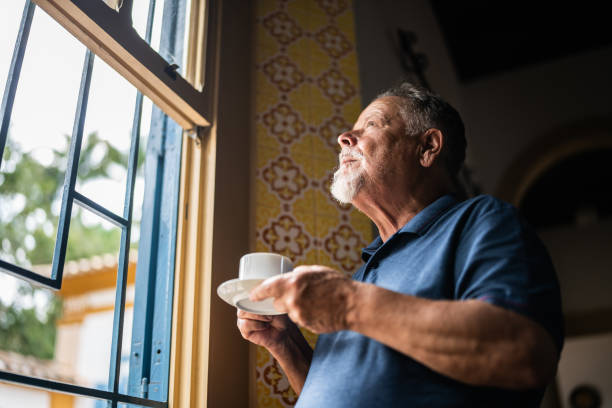 istock Contemplative senior man drinking coffee and looking through the window 1368002931