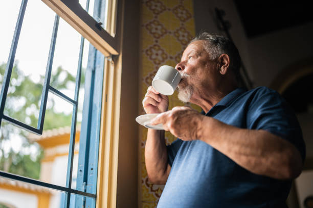 istock Contemplative senior man drinking coffee and looking through the window 1368002964