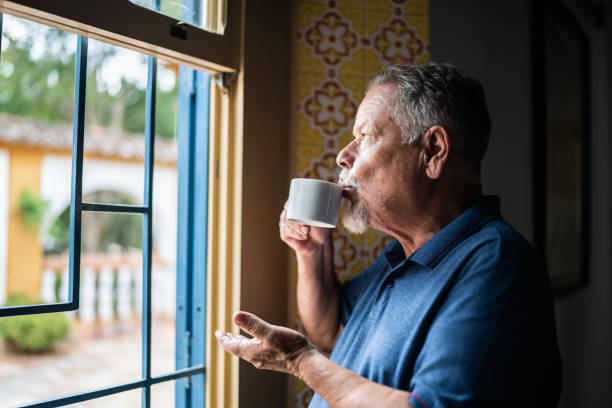 istock Contemplative senior man drinking coffee and looking through the window 1368003008