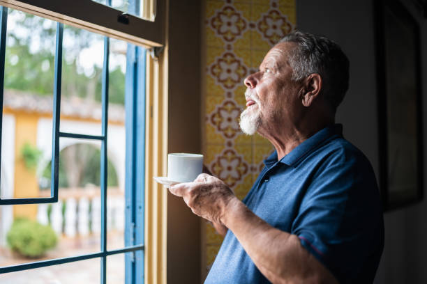 istock Contemplative senior man drinking coffee and looking through the window 1368003025