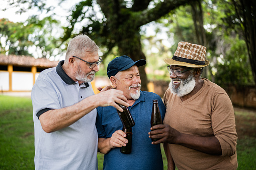 Senior men toasting with beer bottles outdoors