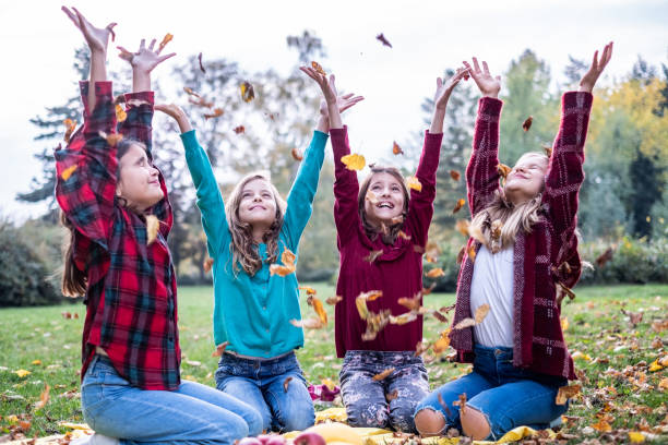 four beautiful girls throw colorful leaves