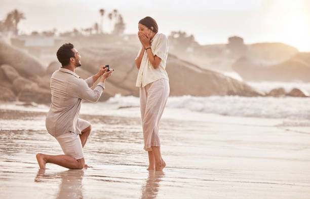 foto de un joven proponiéndole matrimonio a su novia en la playa - anillo de compromiso fotografías e imágenes de stock