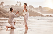 Shot of a young man proposing to his girlfriend on the beach