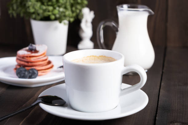 Cafe espresso macchiato layered coffee in a see through white glass coffee cup. The cup is on a wooden background. Horizontal orientation