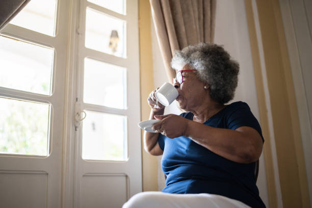 istock Contemplative senior woman looking through the window while drinking coffee at home 1368004785