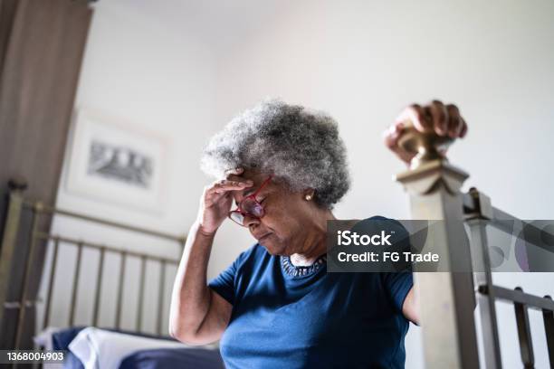 Senior woman with headache sitting in the bed at home