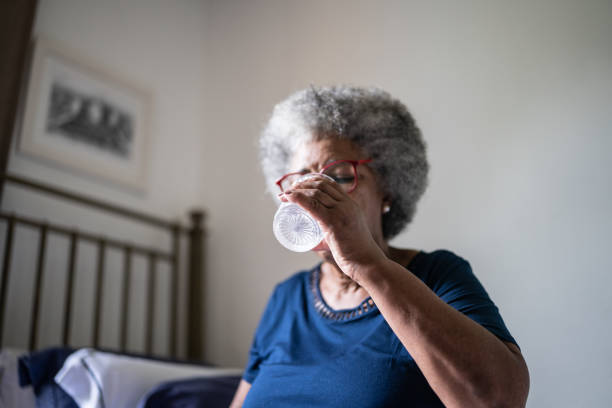 istock Senior woman drinking water at home 1368004968