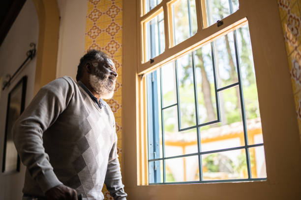istock Contemplative senior man looking through the window 1368004991
