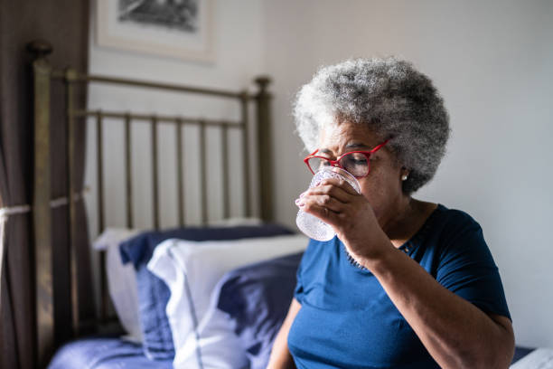 istock Senior woman drinking water at home 1368005013