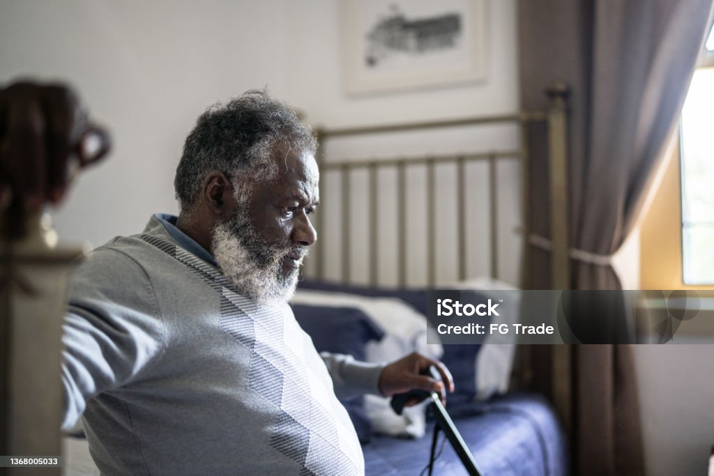 Contemplative senior man sitting in the bed at home Senior Adult Stock Photo