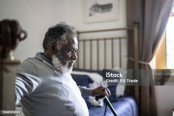 Contemplative Senior Man Sitting In The Bed At Home Stock Photo - Download Image Now