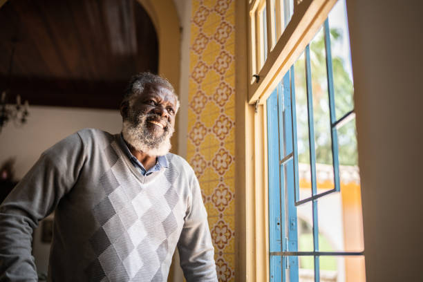 istock Contemplative senior man looking through the window 1368005034