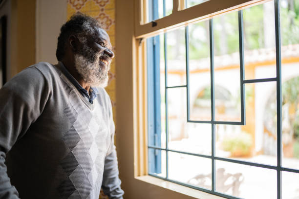 istock Contemplative senior man looking through the window 1368005089
