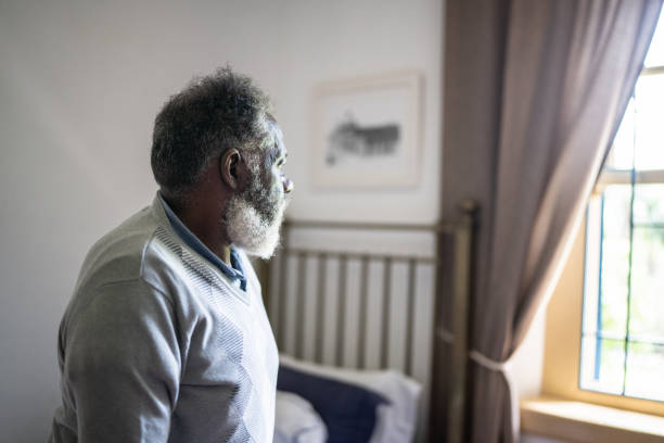 istock Contemplative senior man looking through the window at home 1368005610