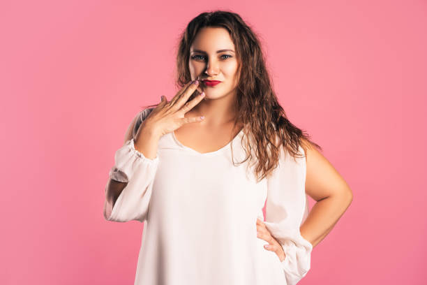 istock Doubting plus size model in white dress on pink background 1368006984