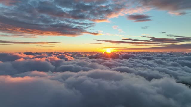 Sun comes out from behind a cloud in the early morning above the clouds.  Flying above the clouds illuminated by the morning sun. Epic sunrise in the sky