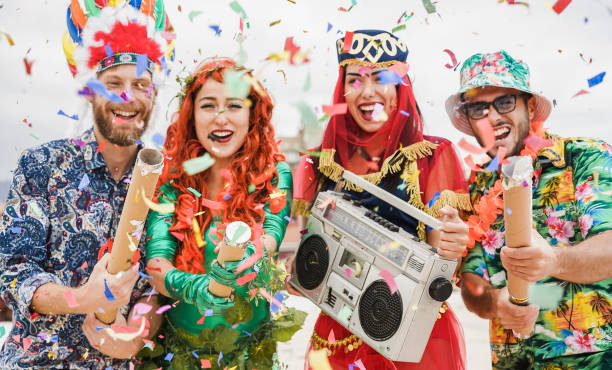 happy dressed people celebrating at carnival party throwing confetti - focus on left girl hands - optocht stockfoto's en -beelden