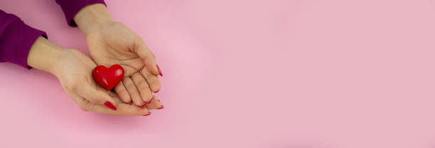 istock valentine. heart in hands on a pink background. 1368007663