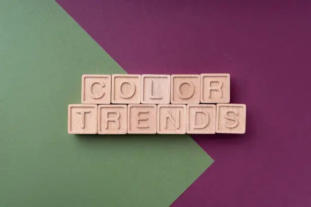 Photo of Color trends 2022, flat, lay, top view. The inscription is made of eco-friendly wooden cubes. Concept trends 2022 against the background of burgundy and green. Bright geometric background