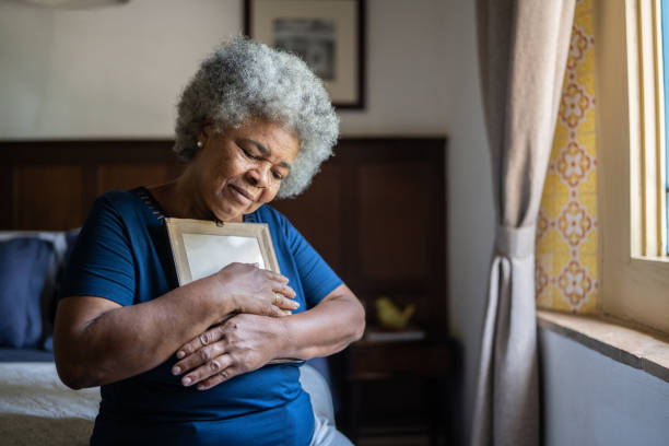 istock Senior woman holding a picture frame missing someone at home 1368009918