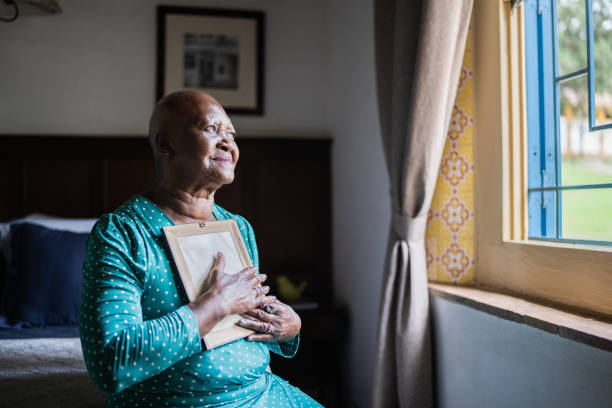 Senior woman holding a picture frame missing someone at home