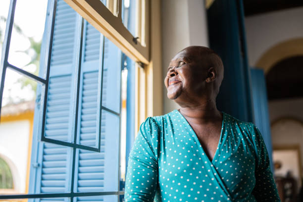 istock Contemplative senior woman looking through the window 1368010031