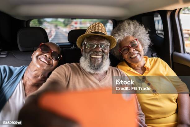 Senior Friends Filming Or Taking Selfies On The Mobile Phone Inside A Car On A Road Trip Stock Photo - Download Image Now