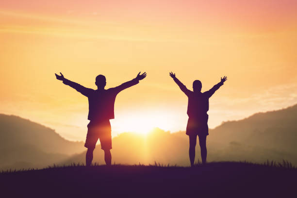 istock Couple rising hands on sunset sky at nature field abstract background. 1368010318