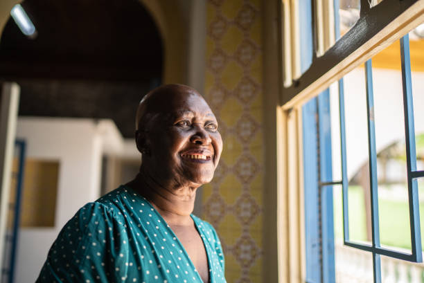 istock Senior woman looking through the window at home 1368011437