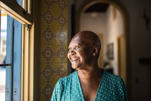 istock Senior woman looking through the window at home 1368011443