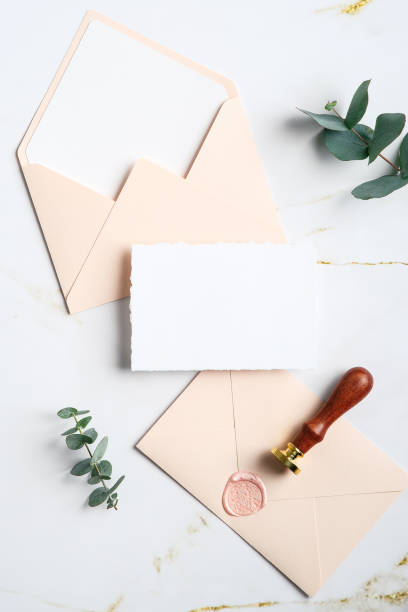 istock Wedding stationery set. Top view blank paper card, envelopes, wax seal stamp, eucalyptus branches on white marble table. Top view. Flat lay. 1368015903