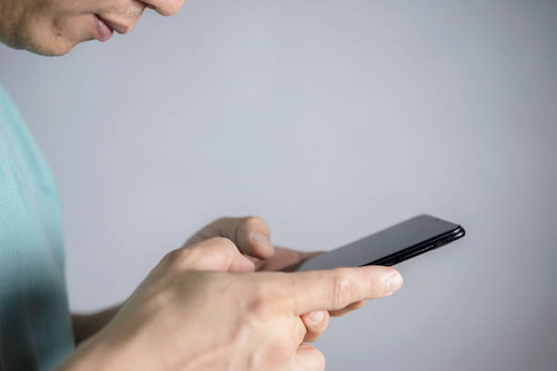 istock Attractive bearded businessman using smartphone while sitting on sofa at his home. 1368016099
