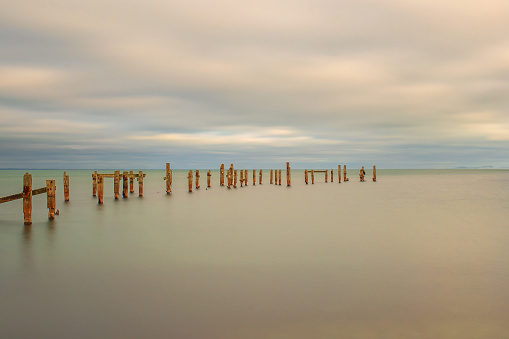 A minimalist image with the old Swanage Pier stanchions sticking out with a slow shutter pink hued sea